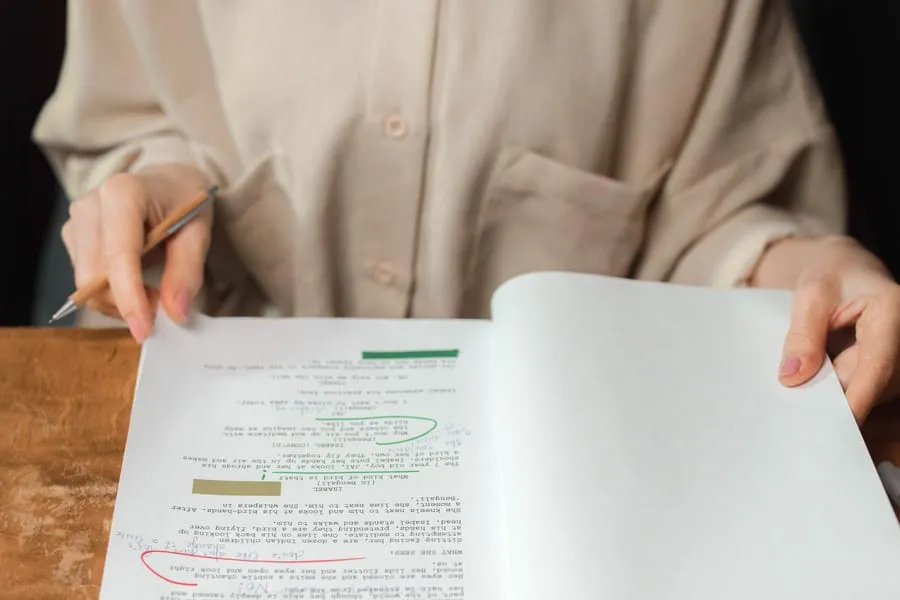 An actor reviews notes at a table in natural light.
